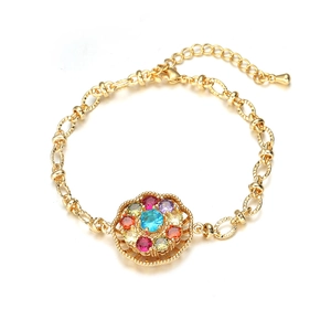 Golden bracelet with a rotating colorful rhinestone floral pendant on a white background