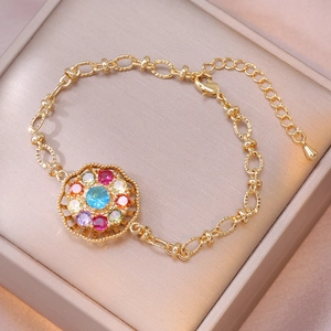Gold charm bracelet with a colorful rotating flower pendant and blue zircon on silk