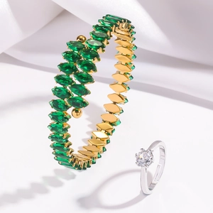 Détail d'un bracelet de zircones marquise émeraude et bague en diamant sur soie blanche