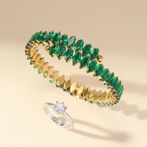 Détail d'un jonc doré avec pierres marquises vertes et d'une bague diamant argent