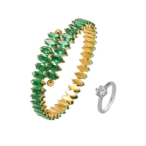 Bracelet en acier doré avec zircons émeraude et bague solitaire argentée sur fond blanc