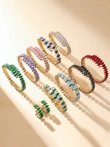 Detail of luxury gold bracelets and earrings set with colorful marquise-cut cubic zirconia