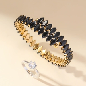 Detailed close-up of gold bangle with black marquise gems and a silver zircon ring