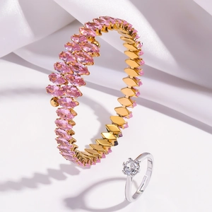 Detailed shot of a gold bangle with pink marquise zircons and a silver solitaire ring