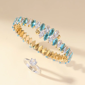 Detail showing a gold bracelet with blue and white marquise zircons and a silver ring