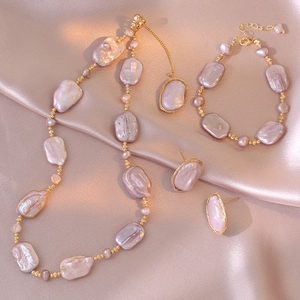 Baroque natural freshwater pearl necklace, bracelet, and earring set on silk background