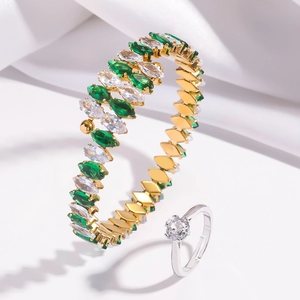 Detailed macro view of gold bracelet with green zircons and sparkling silver zircon ring