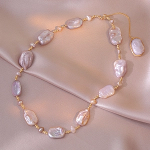 Baroque irregular freshwater pearl necklace with gold beads on purple silk fabric