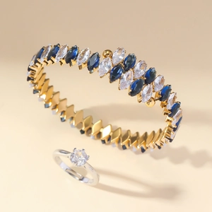 Detailed shot of gold open cuff with colorful marquise stones and silver solitaire ring