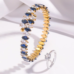 Macro detail of gold marquise zircon bracelet and silver solitaire ring on white silk