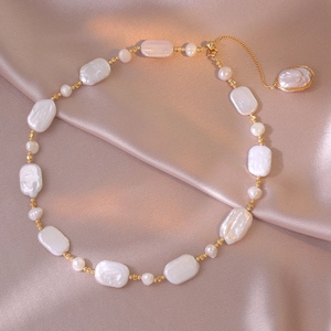 Macro detail of Baroque freshwater pearl necklace with gold beads on silk fabric