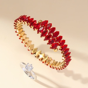 Close-up of gold-plated bangle with red marquise zircon stones and a solitaire diamond ring