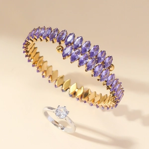 Close-up of golden bangle set with purple marquise stones and classic silver diamond ring