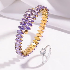 Detail of gold spiral bangle with purple stones and silver solitaire ring on silk