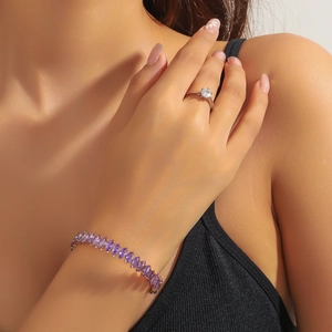 Detail of gold bracelet with purple marquise zircon and silver ring on a female model