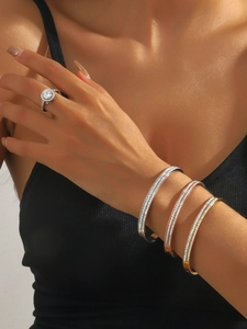 Detailed shot of stacked rhinestone bangles and sparkling solitaire ring on model wrist