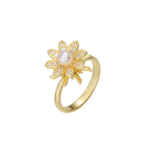 Détail macro d'une bague marguerite dorée avec zircons brillants et perle centrale