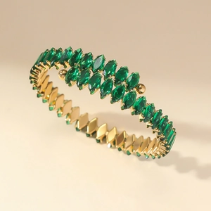 Bracelet jonc doré élégant avec zircons vert émeraude taille marquise sur fond beige