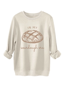 Détail de l'imprimé graphique pain au levain et texte sur le sweat-shirt beige clair