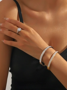 Gros plan de bracelets étincelants or et argent et d'une bague sur la main d'un mannequin