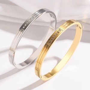 Stacked gold and silver ribbed titanium bracelets with shimmering white zircon stones