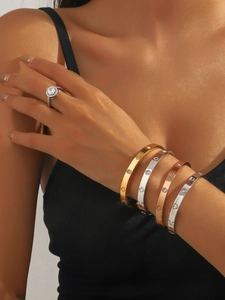 Détail de femme portant des bracelets en acier titane avec trèfles et motifs de cœur