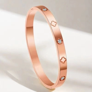 Détail du bracelet en acier titane or rose avec diamants incrustés et motifs trèfles