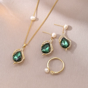Detailed set of gold-plated freshwater pearl and green zircon jewelry on silk fabric