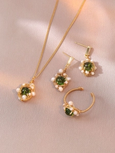 Détail d'un ensemble de bijoux fait main en fil doré avec perles et pierres vertes