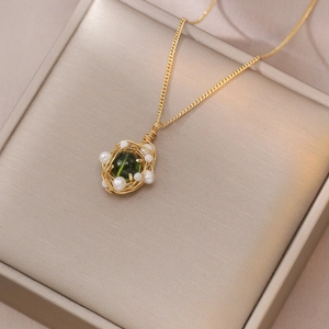 Collier nid d'oiseau avec gemme verte et perles d'eau douce sur boîte cadeau luxe