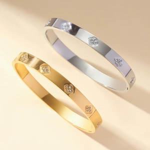 Polished stainless steel gold and silver clover bracelets with diamond accents in soft light