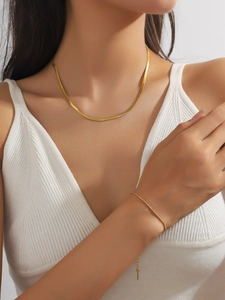 Détail d'un ensemble de collier et bracelet en maille serpent dorée en acier inoxydable