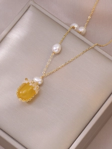 Détail du collier de perles d'eau douce avec pendentif gemme jaune sur velours champagne