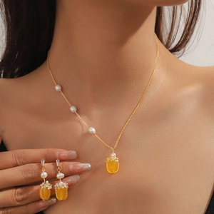 Détail d'un ensemble collier et boucles d'oreilles dorés avec pierres et perles