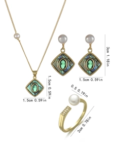 Detailed set of gold jewelry with freshwater pearls and green gems on iridescent shell