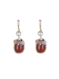 Détail de boucles d'oreilles vintage avec agate rouge, perle blanche et fleurs