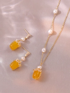 Détail de parure bijoux fleurs agate rouge et perles sur fond de soie rose