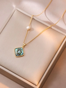 Detail of gold necklace featuring square abalone pendant and green emerald gemstone