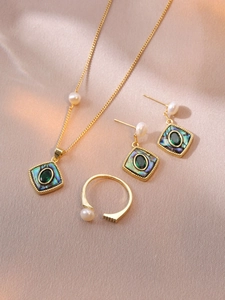 Detail of vintage gold-plated jewelry set with green stones and elegant white pearls