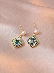 Detail of vintage gold earrings with freshwater pearls and green stones on silk