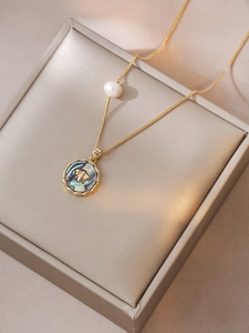 Detail of bee necklace with freshwater pearl and abalone shell on champagne velvet box