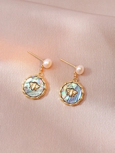 Detail of vintage gold earrings with freshwater pearls and bee embossed abalone shell pendants