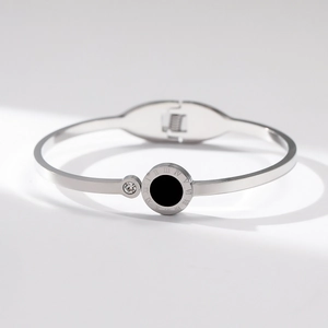 Macro detail of silver stainless steel bangle showing Roman numerals and a small zircon