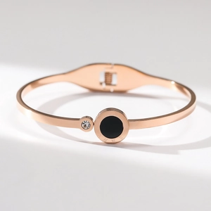 Detailed close-up of rose gold bangle with roman numerals, black inlay and crystal