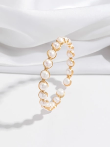 Détail d'un bracelet en fil doré fait main orné de perles d'eau douce blanches naturelles