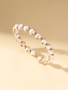 Détail du tressage artisanal en fil doré sur un bracelet jonc ouvert aux perles d'eau douce