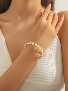 Détail du bracelet en perles d'eau douce enroulé de fil d'or sur le poignet d'une femme