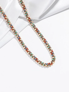 Détail de breloques en émail coloré sur un collier à grosse chaîne cubaine dorée