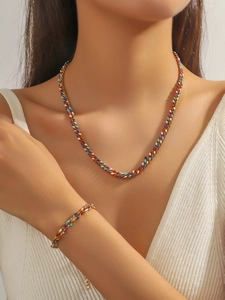 Détail de l'ensemble collier et bracelet en émail coloré sur mannequin avec chaîne dorée