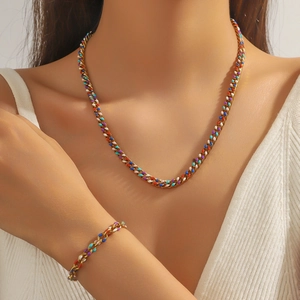 Détail d'une parure de bijoux en émail coloré avec collier et bracelet dorés sur mannequin